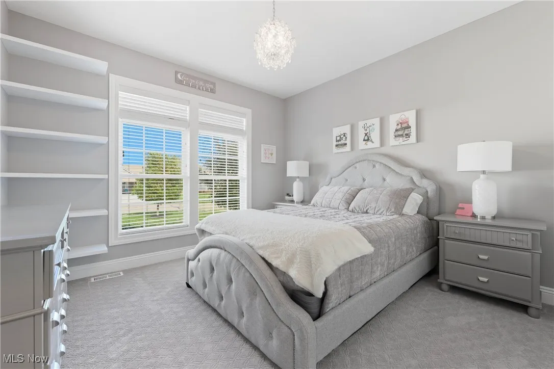 Bedroom featuring light colored carpet and a chandelier