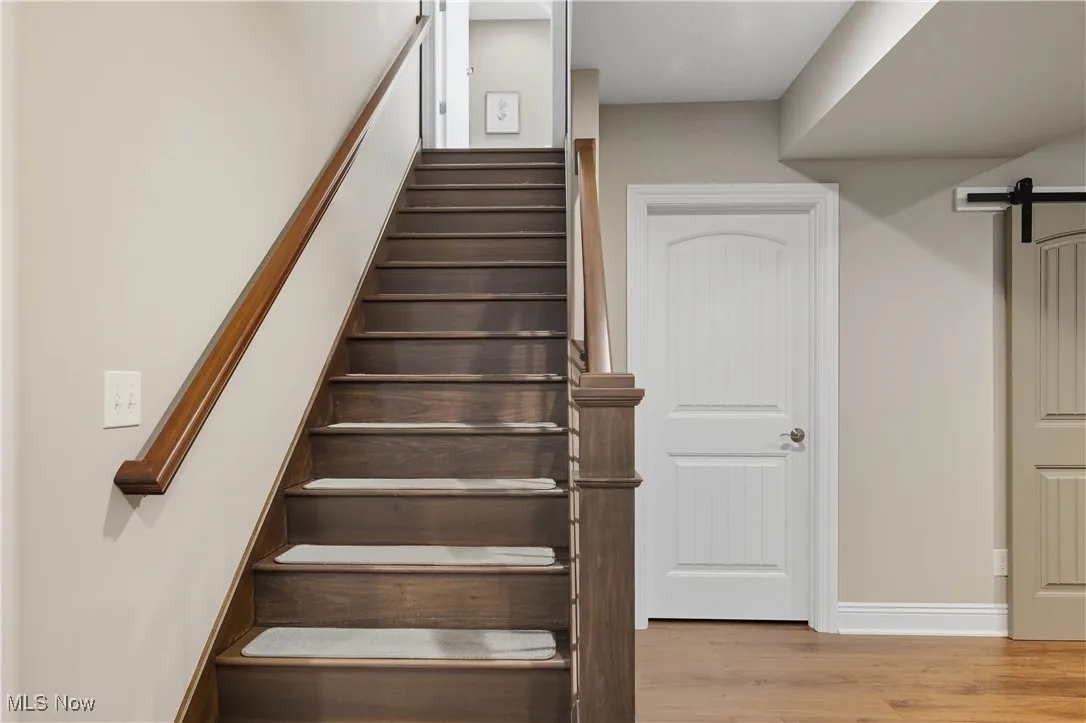 Stairs featuring a barn door and wood finished floors