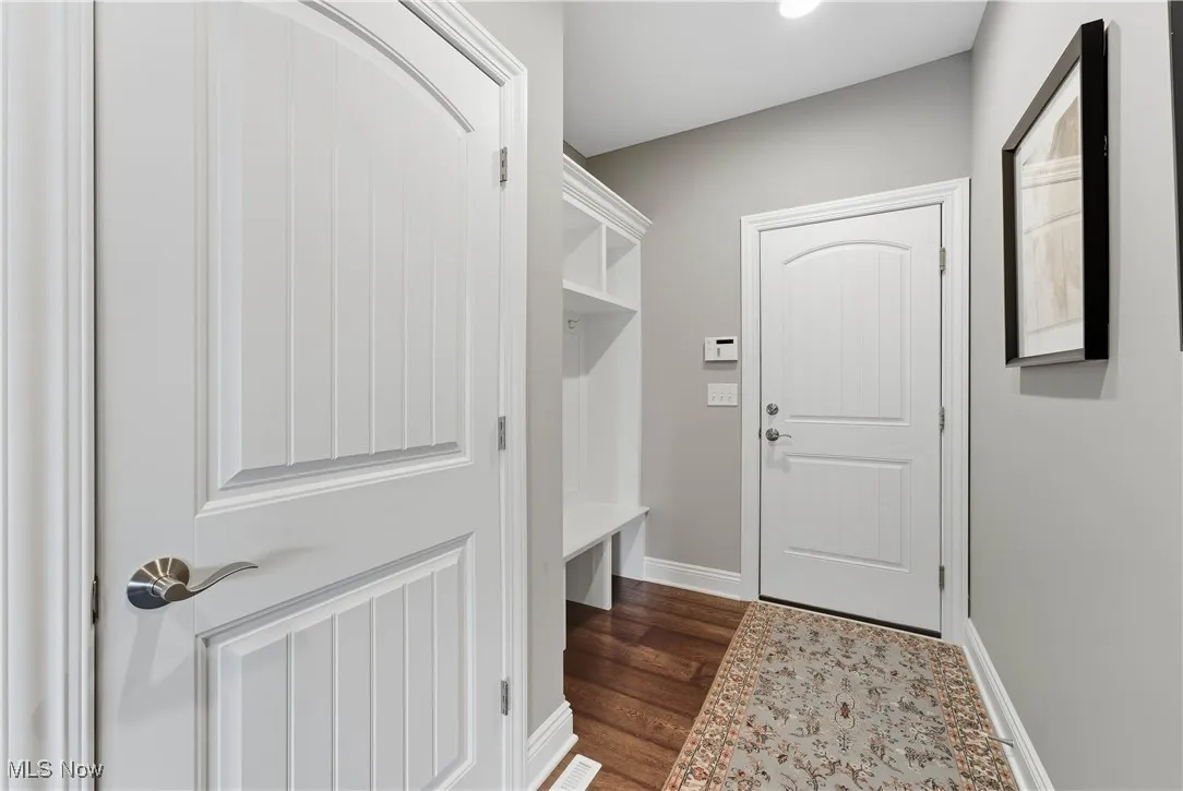 Mudroom featuring dark wood-style floors and baseboards