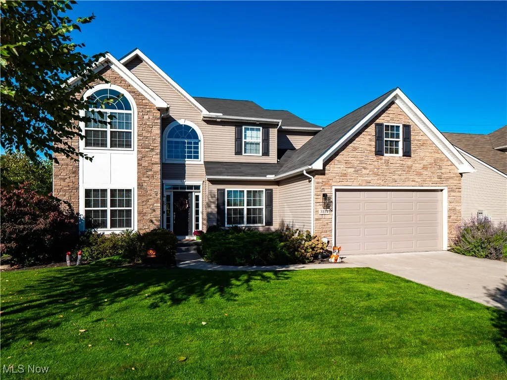 Traditional-style house with driveway, a front yard, and stone siding