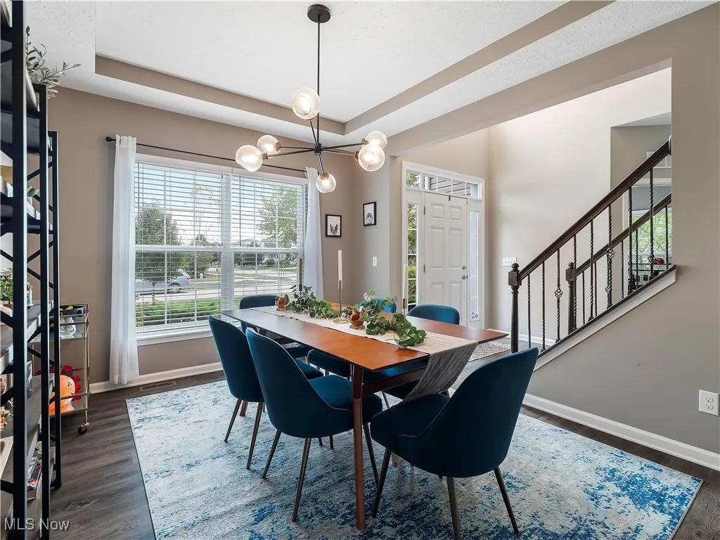 Dining room with stairway, a tray ceiling, and dark wood finished floors