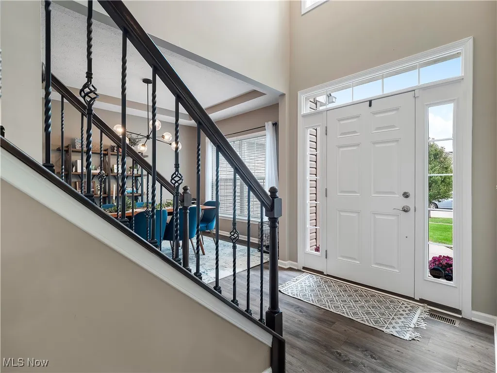 Foyer featuring dark wood-style floors, a chandelier, and stairway