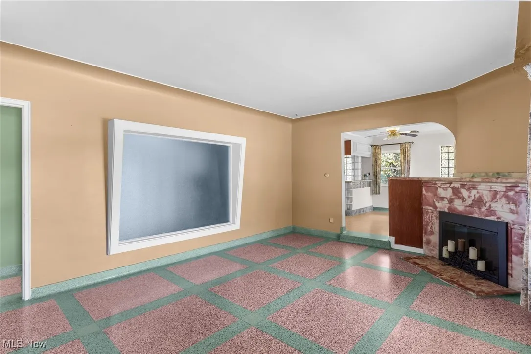 Unfurnished living room featuring a fireplace, ceiling fan, and speckled floor