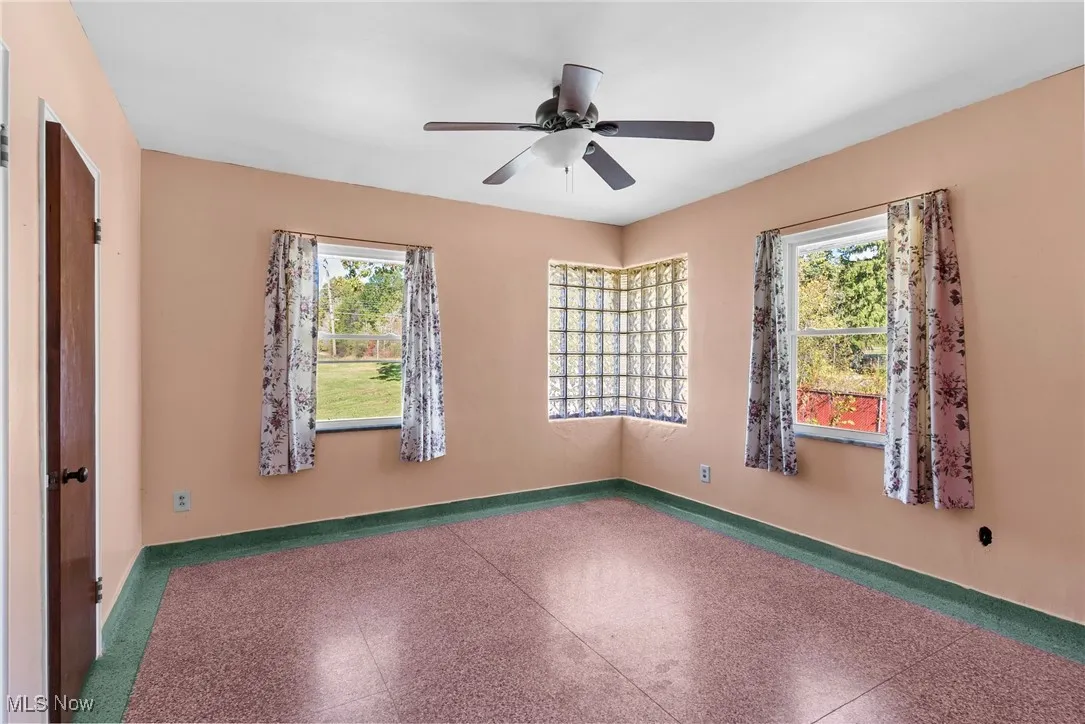 Spare room with speckled floor, plenty of natural light, and a ceiling fan