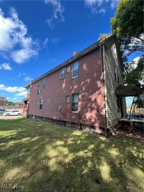 View of side of home with a lawn and a chimney