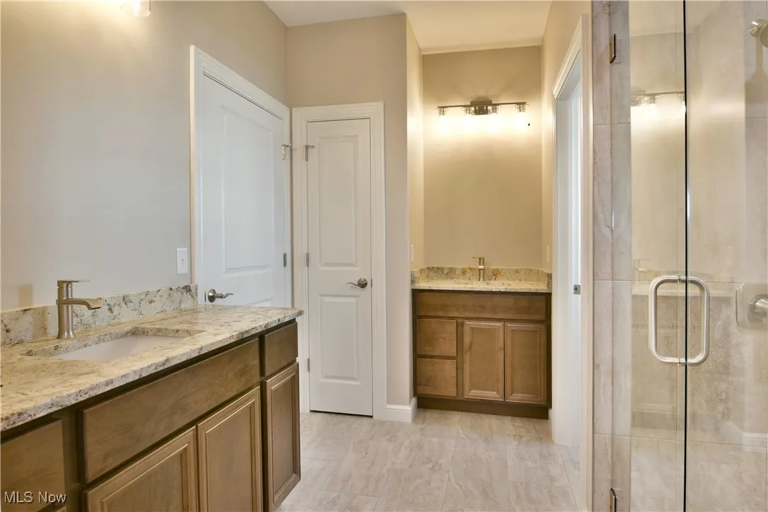 Full bath with a shower stall and two vanities