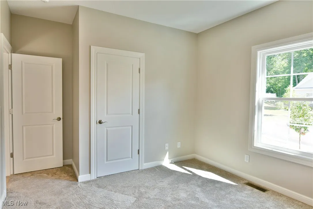Unfurnished bedroom with baseboards and light colored carpet