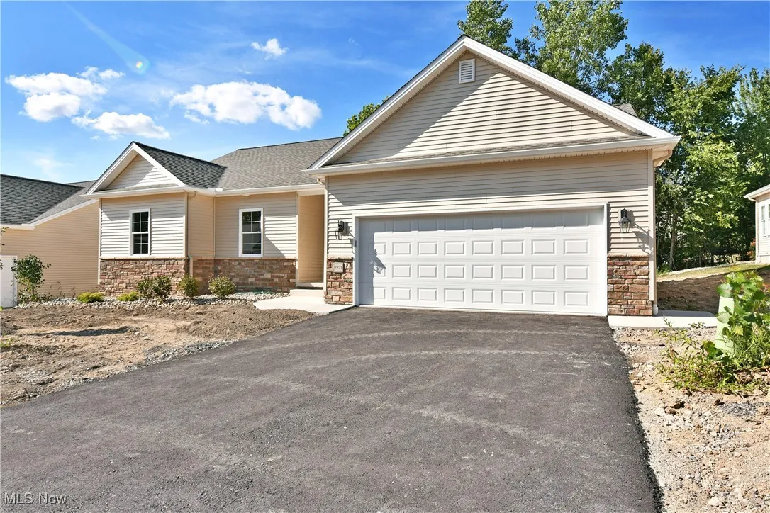 View of front of house featuring asphalt driveway and stone siding