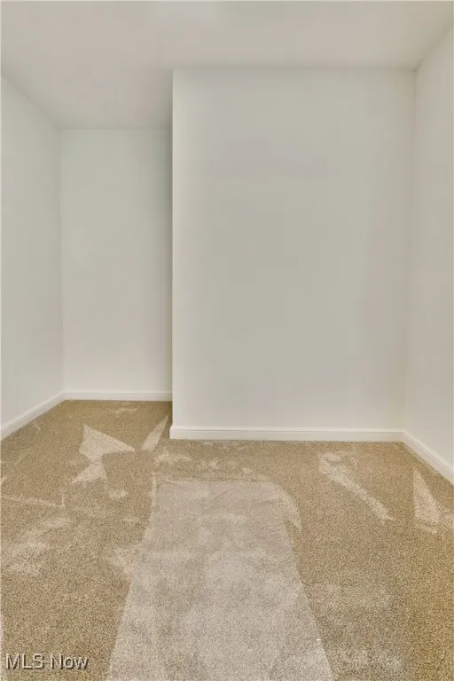Carpeted spare room featuring baseboards