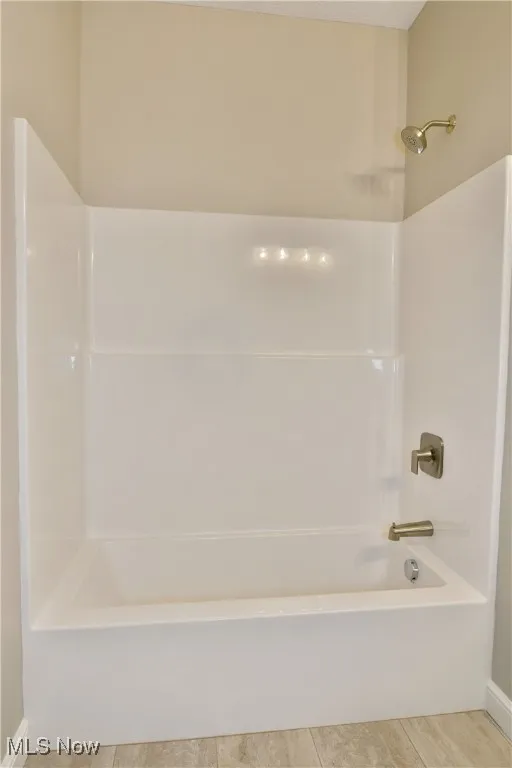 Full bath with washtub / shower combination and light tile patterned floors