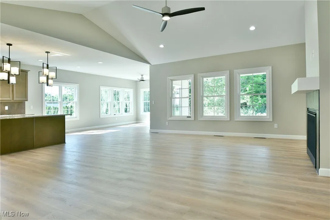Unfurnished living room featuring light wood-style floors, recessed lighting, ceiling fan, a fireplace, and high vaulted ceiling