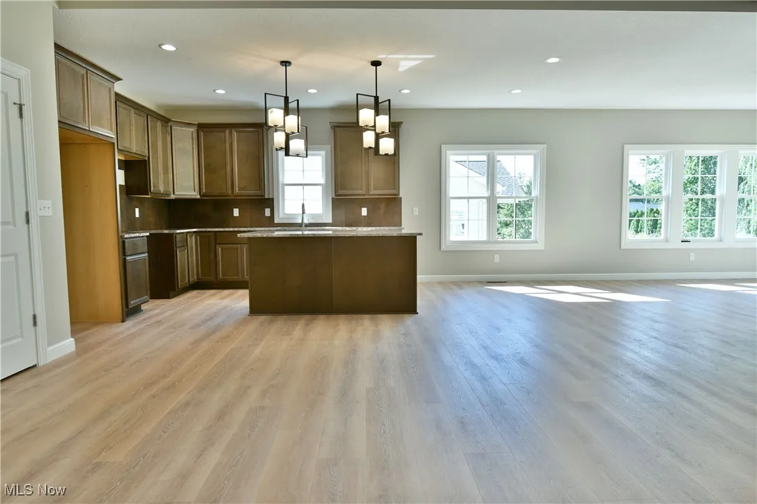 Kitchen featuring open floor plan, pendant lighting, recessed lighting, a center island, and light wood-style floors