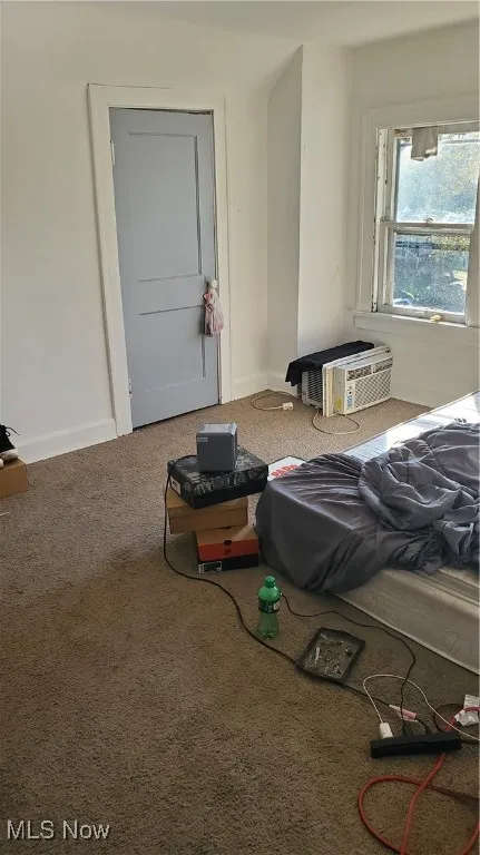 Bedroom with carpet floors and a wall mounted air conditioner