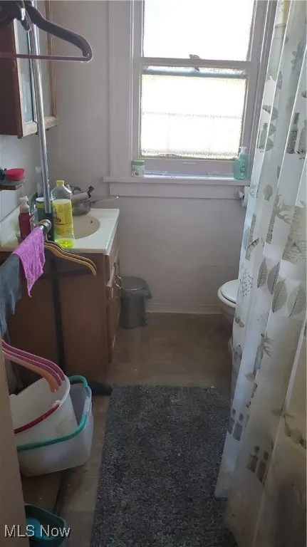 Bathroom with curtained shower, vanity, and dark tile patterned floors