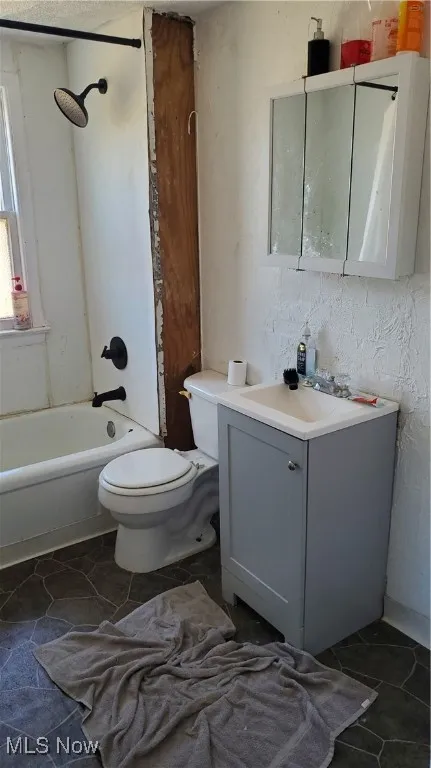 Bathroom with vanity, shower / bathtub combination, and dark tile patterned floors
