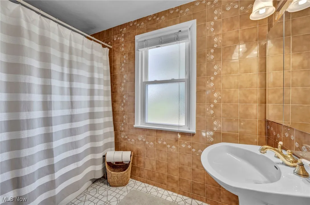 Full bath featuring tile walls, a shower with curtain, and tile patterned flooring