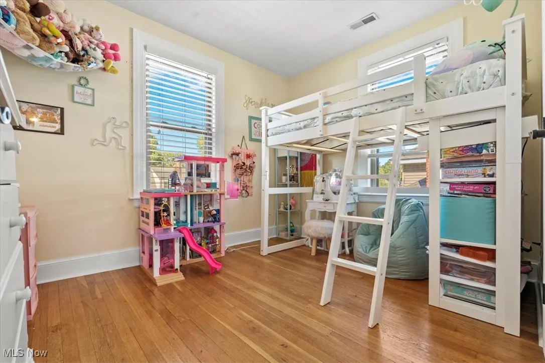 Bedroom with multiple windows and light wood-style flooring
