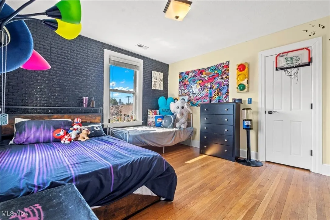 Bedroom with hardwood / wood-style flooring and brick wall