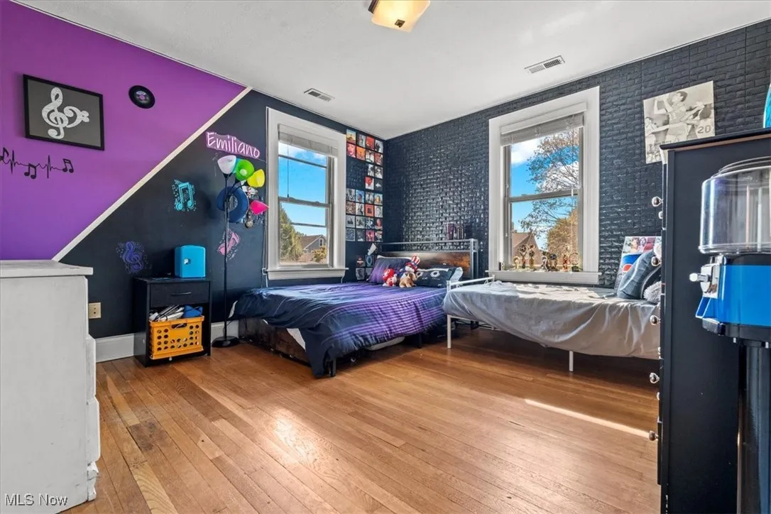 Bedroom with light wood-type flooring and brick wall