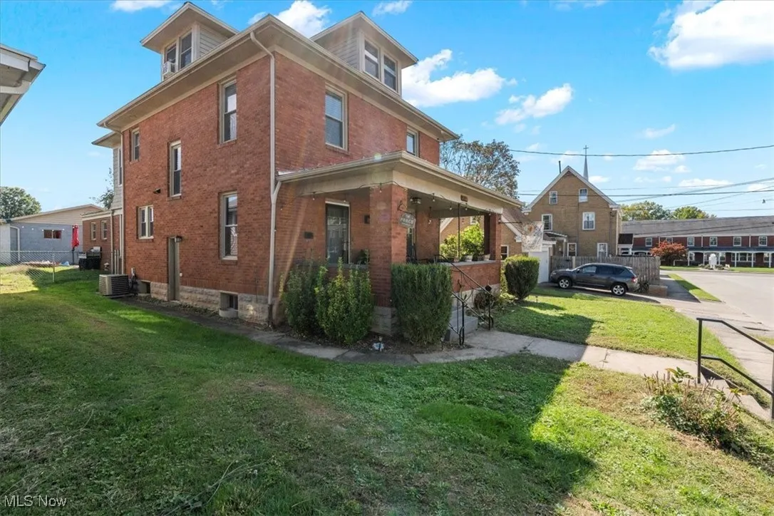Back of property with a fire pit, a fenced backyard, a patio, and brick siding