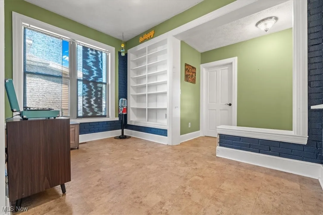 Unfurnished room featuring built in shelves and baseboards