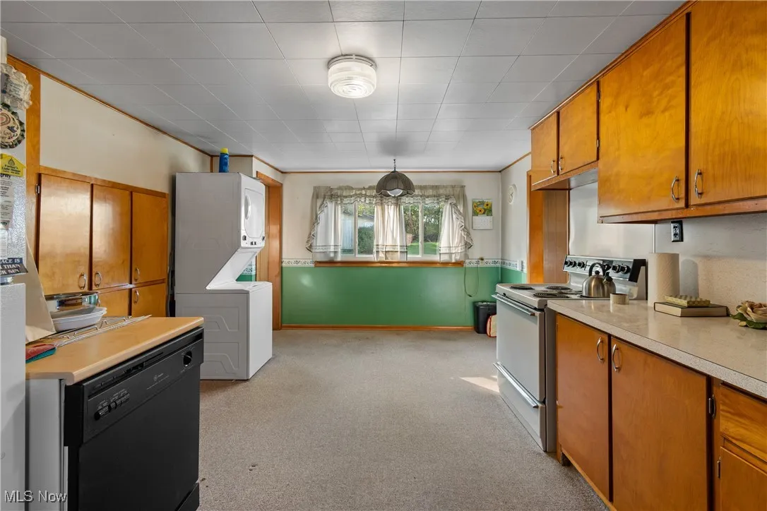 Kitchen with brown cabinets, light countertops, electric stove, black dishwasher, and crown molding