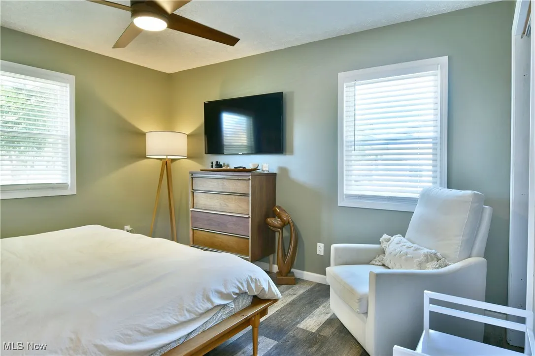 Bedroom featuring dark wood-style flooring, a ceiling fan, and multiple windows