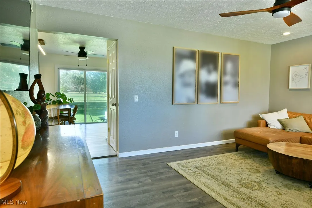 Living area featuring ceiling fan, a textured ceiling, and dark wood finished floors