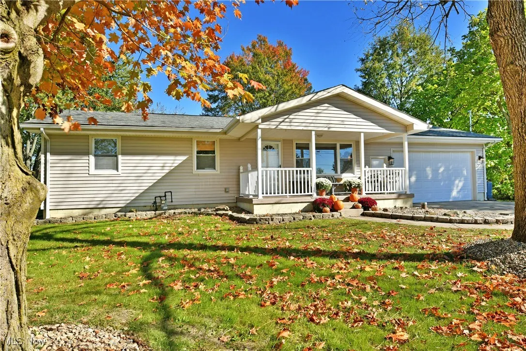 Single story home with a porch, a front yard, a garage, and concrete driveway
