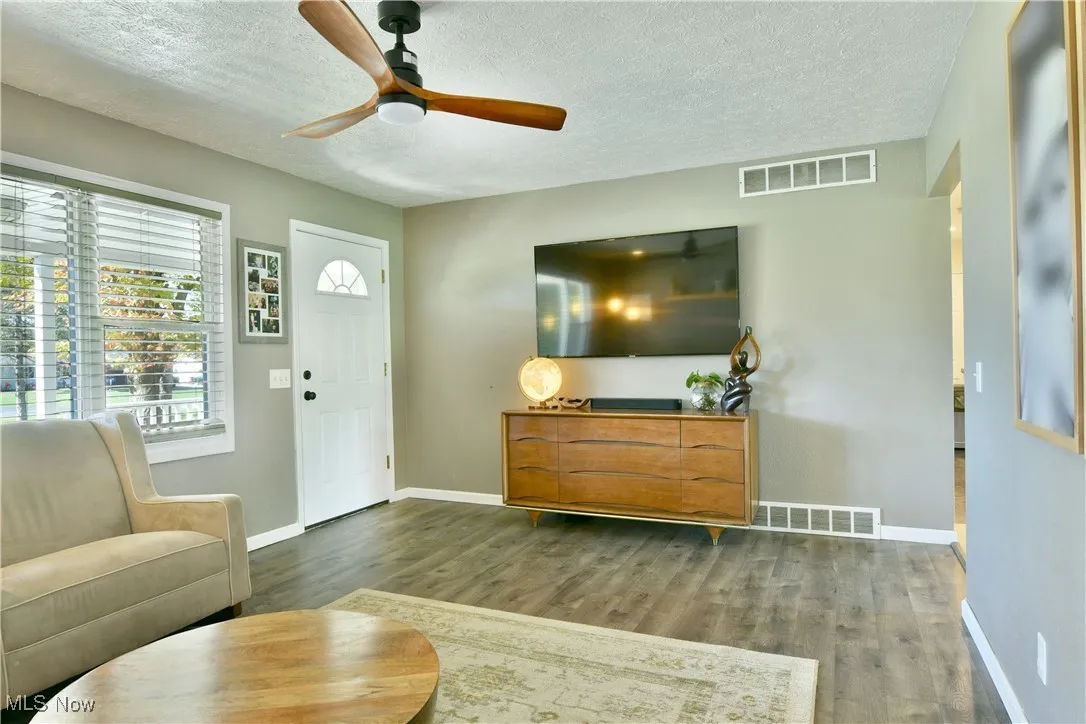 Living room featuring a textured ceiling, wood finished floors, and ceiling fan