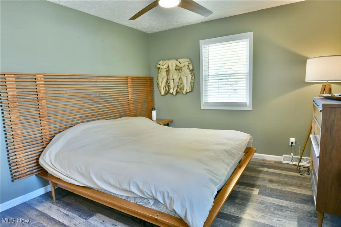 Bedroom featuring dark wood-type flooring, a textured ceiling, and ceiling fan
