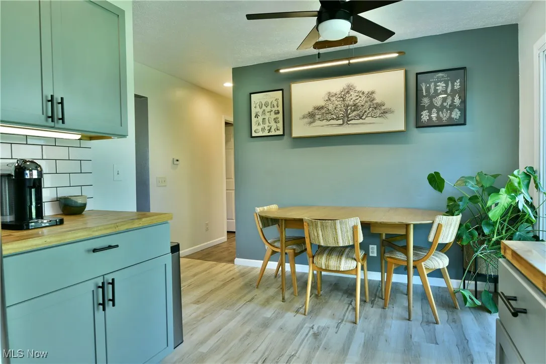 Dining room featuring light wood-style floors, a ceiling fan, and a textured ceiling