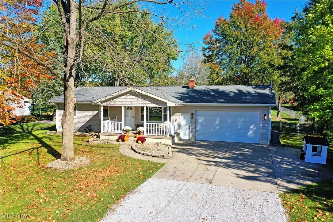 Single story home featuring concrete driveway, covered porch, an attached garage, and a chimney