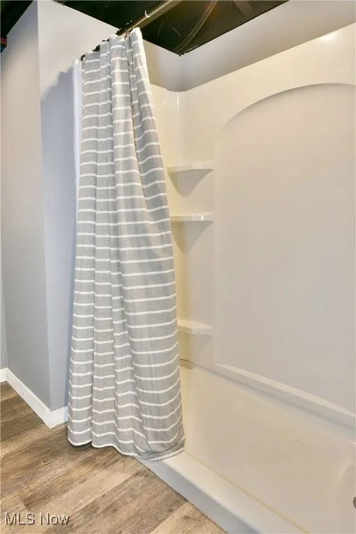 Bathroom with a shower stall and wood finished floors