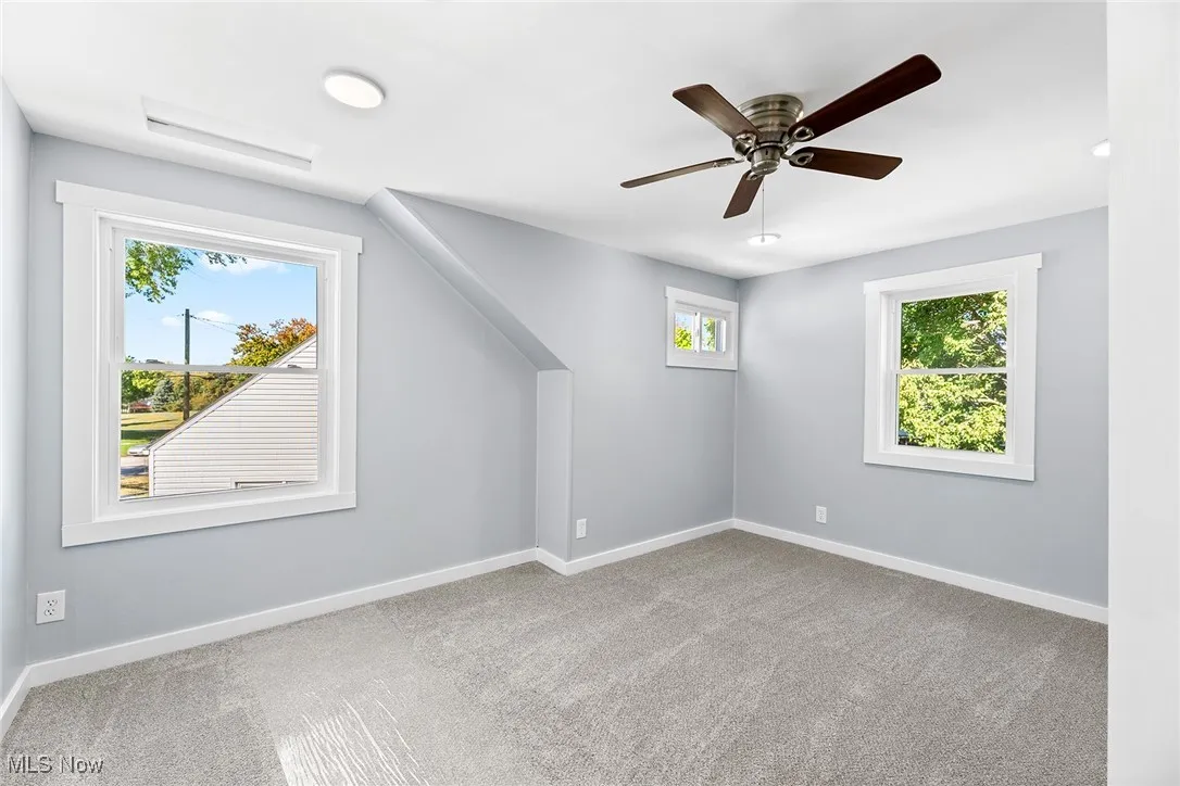 Unfurnished room with light colored carpet and ceiling fan