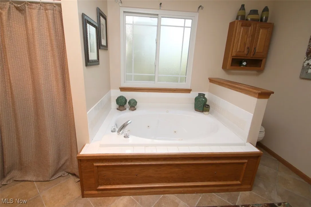 Full bath with a shower with shower curtain, a whirlpool tub, and tile patterned flooring