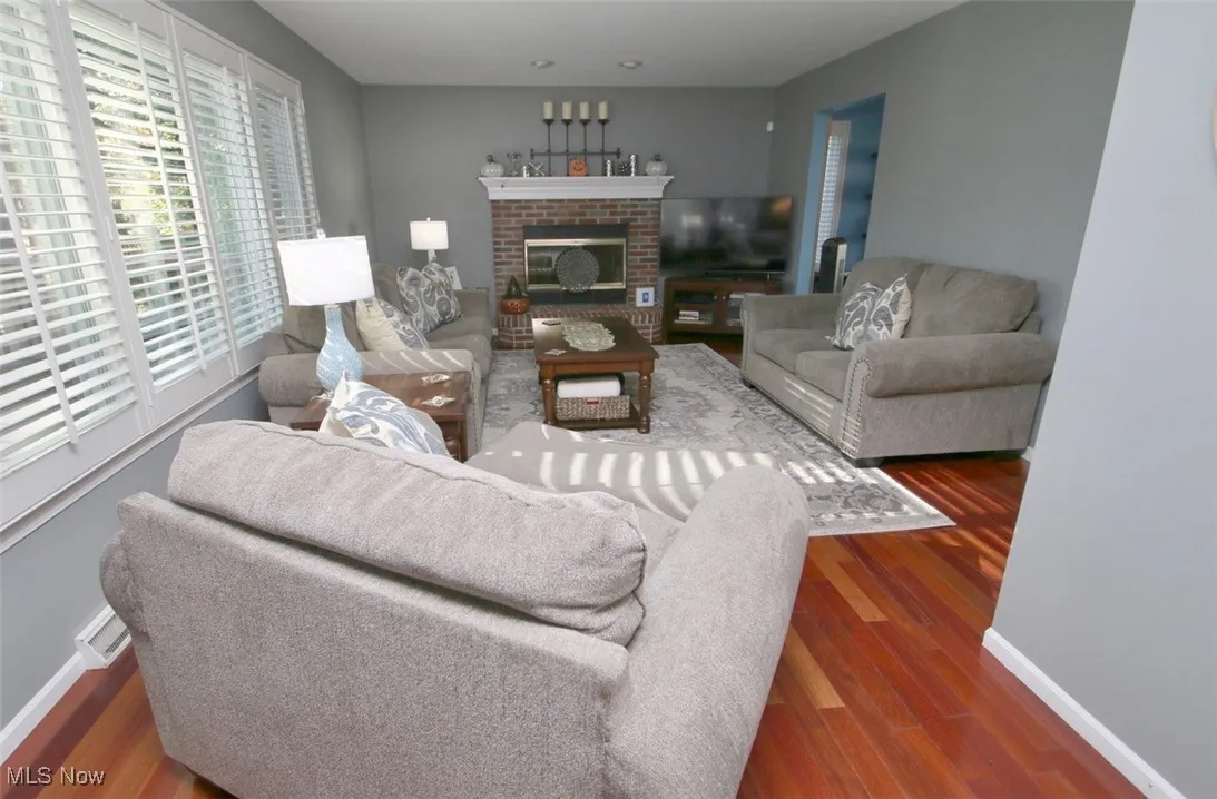 Living area featuring dark wood-style floors and a brick fireplace