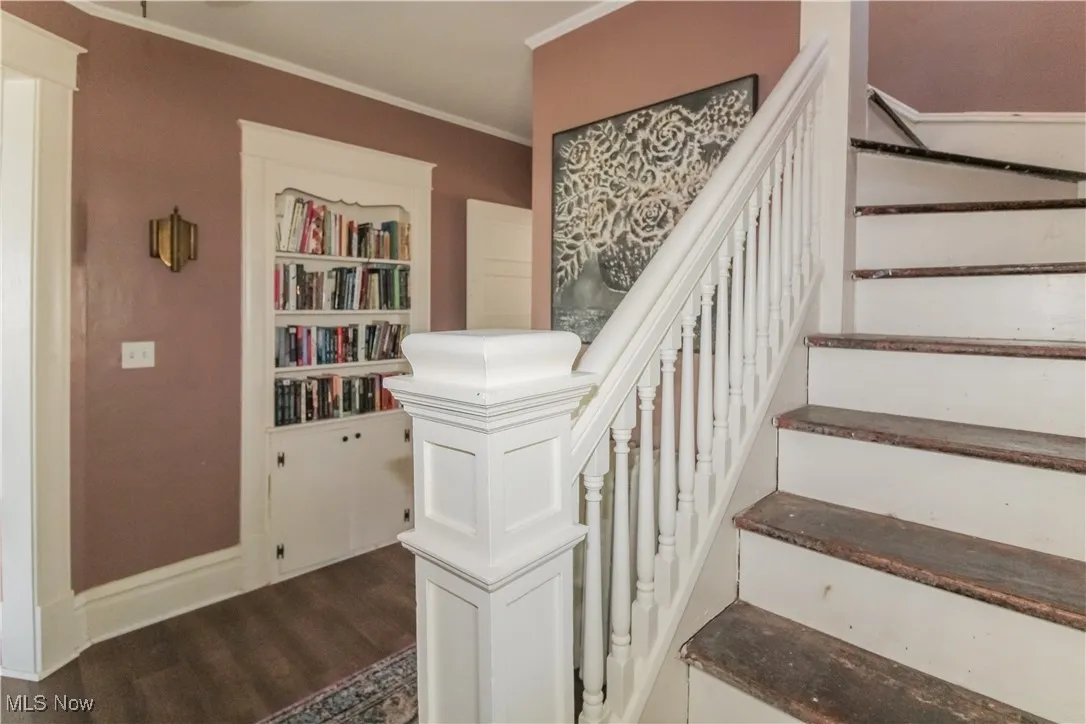 Staircase featuring wood finished floors and crown molding