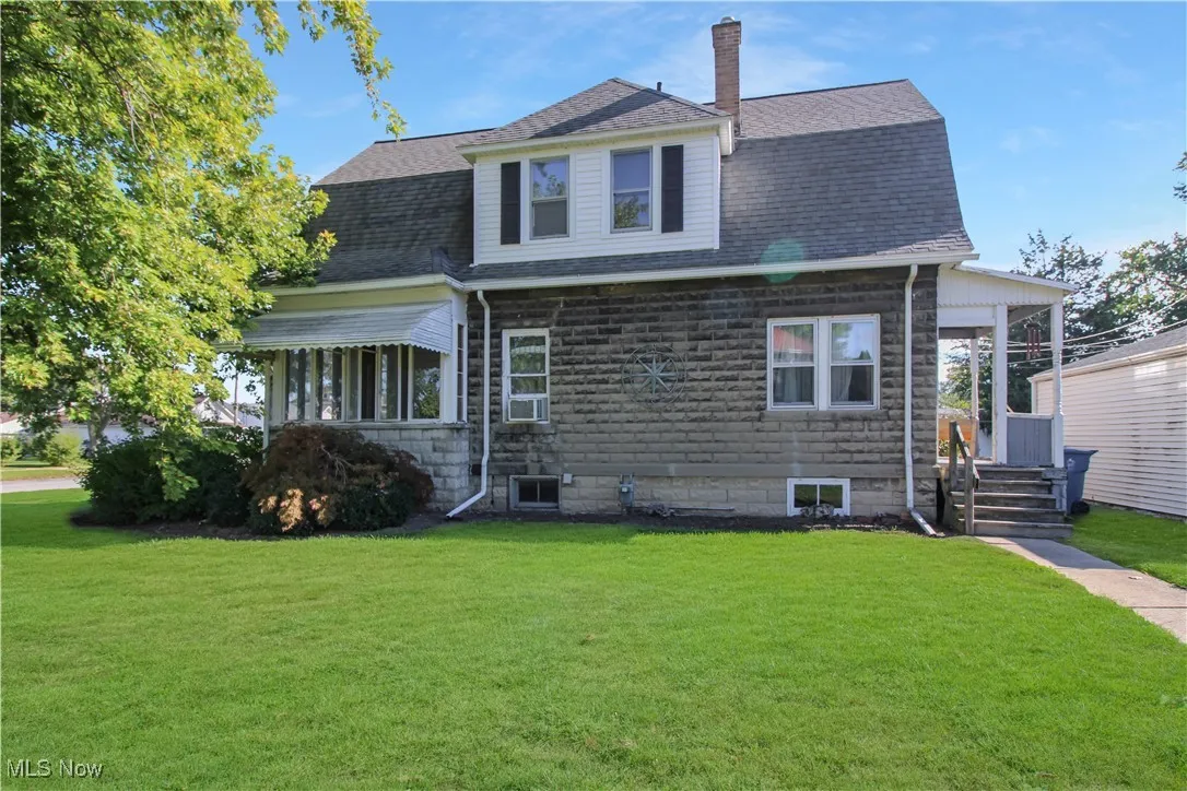 Rear view of property with a yard, a shingled roof, and a chimney