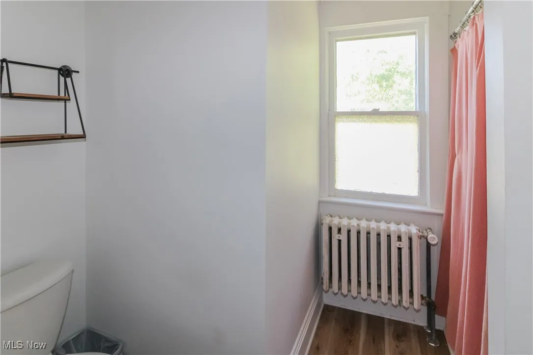 Bathroom featuring radiator heating unit, dark wood-style flooring, and a shower with curtain