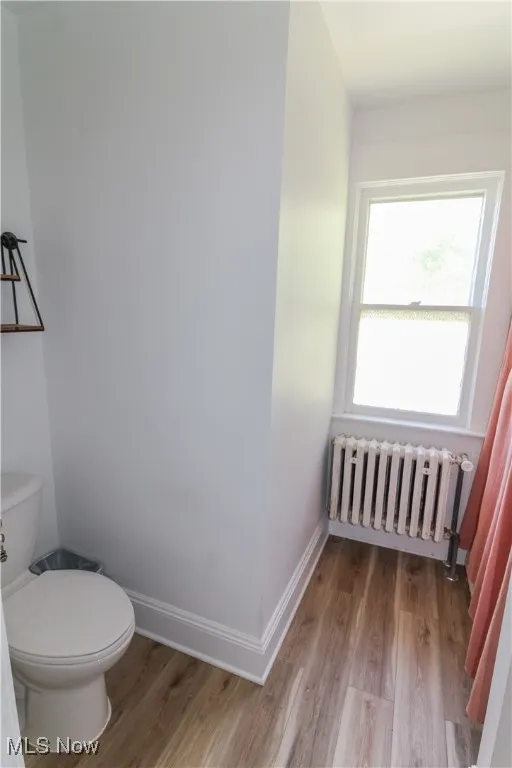 Bathroom with light wood-style flooring and radiator heating unit