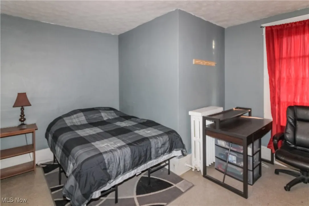 Bedroom with a textured ceiling, light carpet, and an office area