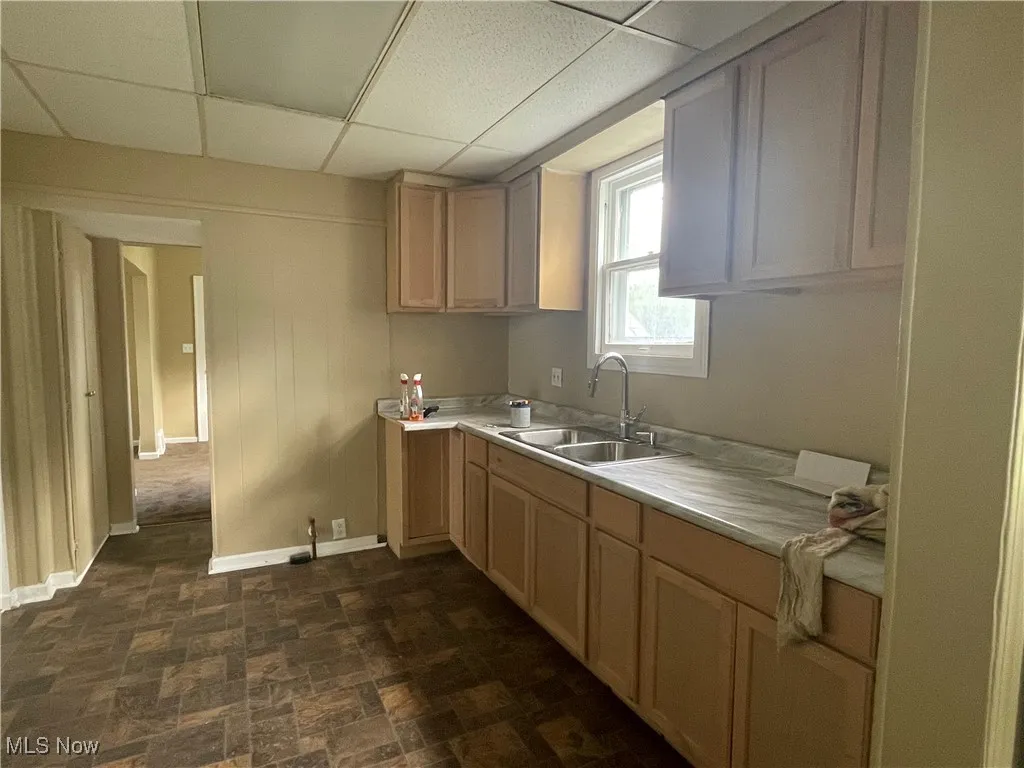 Kitchen with a paneled ceiling, light countertops, and light brown cabinets