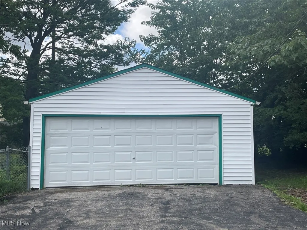 Detached garage featuring view of wooded area