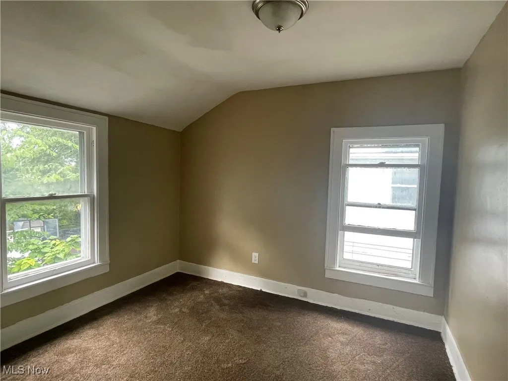 Bonus room featuring lofted ceiling and dark colored carpet