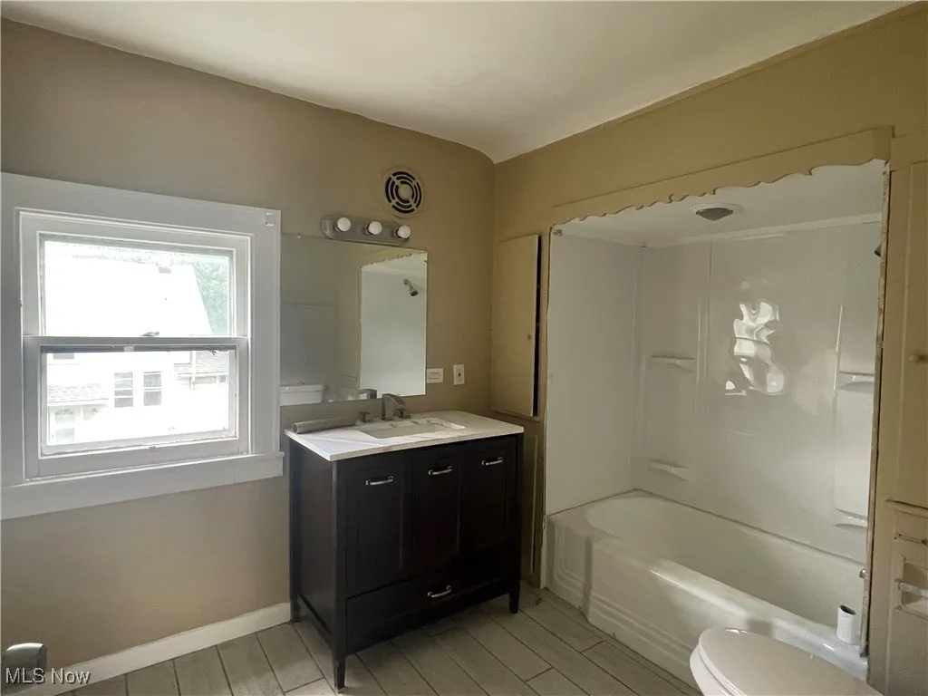 Full bath featuring vanity, shower / washtub combination, and light wood-style flooring