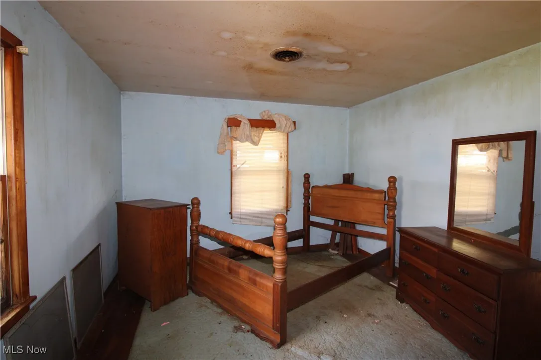 Bedroom with unfinished concrete flooring and a ceiling fan