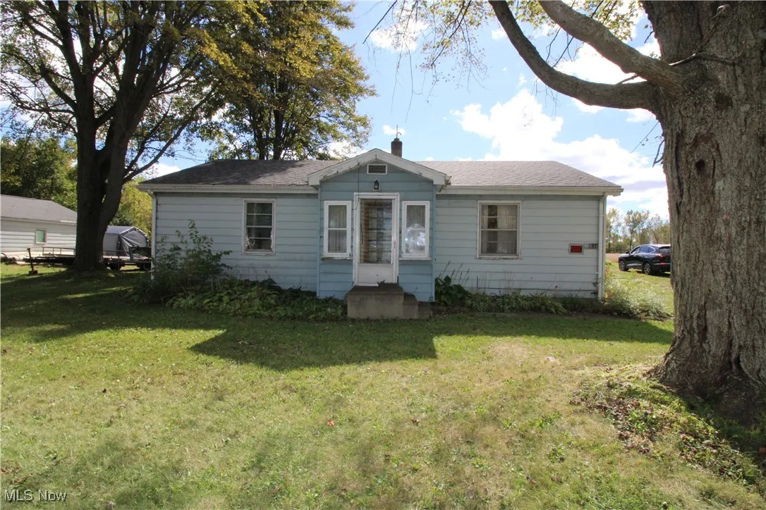 View of front of home featuring a front yard, a chimney, and a shingled roof