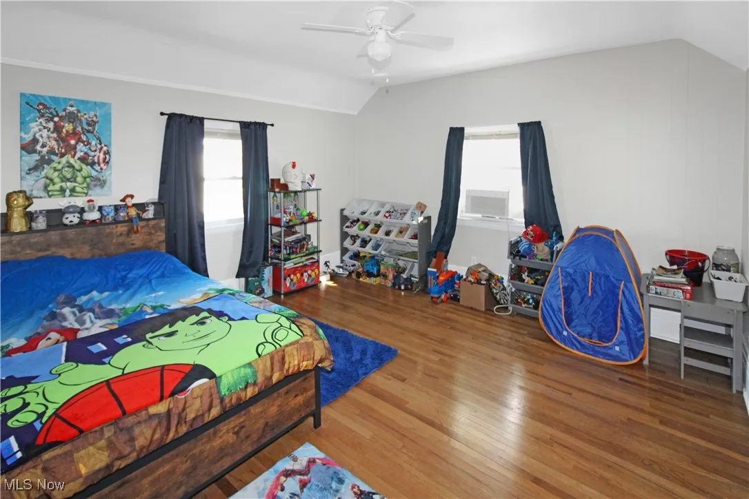 Bedroom with wood-type flooring, multiple windows, a ceiling fan, and lofted ceiling