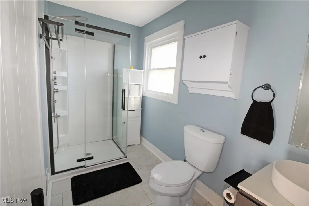 Full bathroom with vanity, a stall shower, and light tile patterned floors